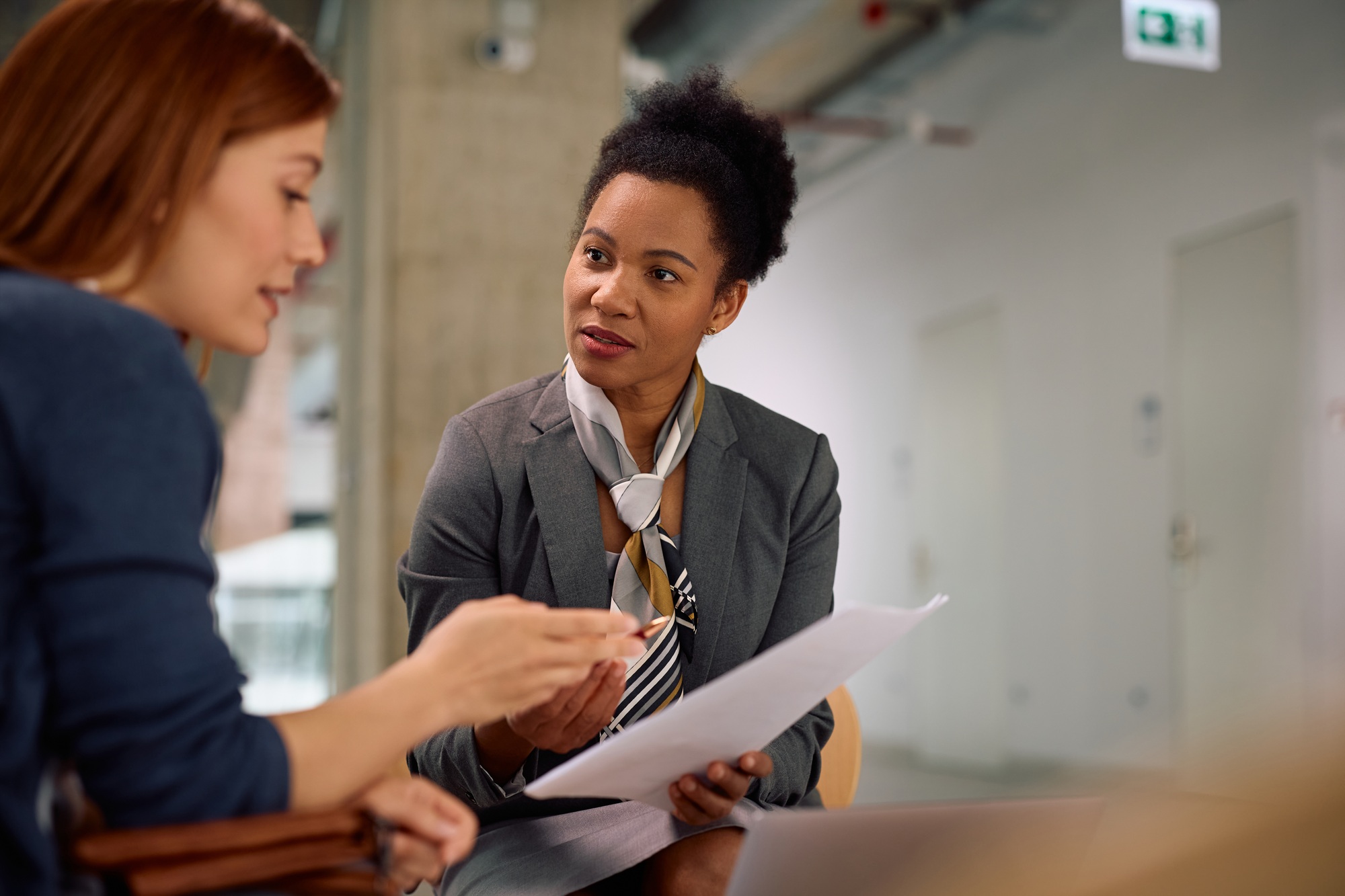 Black insurance agent and her client analyzing financial reports during a meeting in the office.