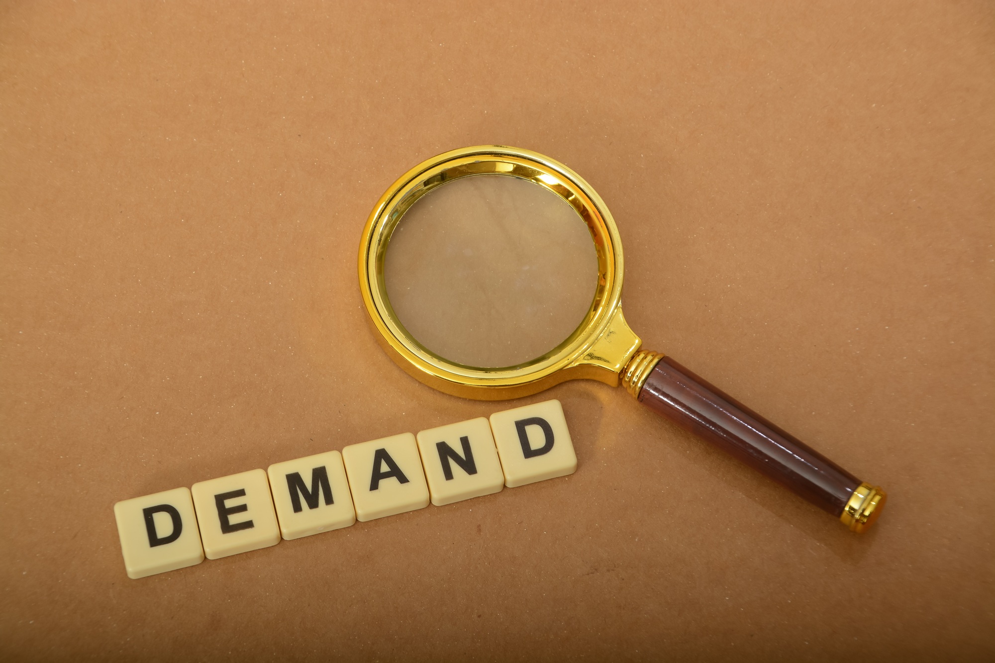 Magnifying glass with text DEMAND. buyers to purchase a particular quantity of goods or services